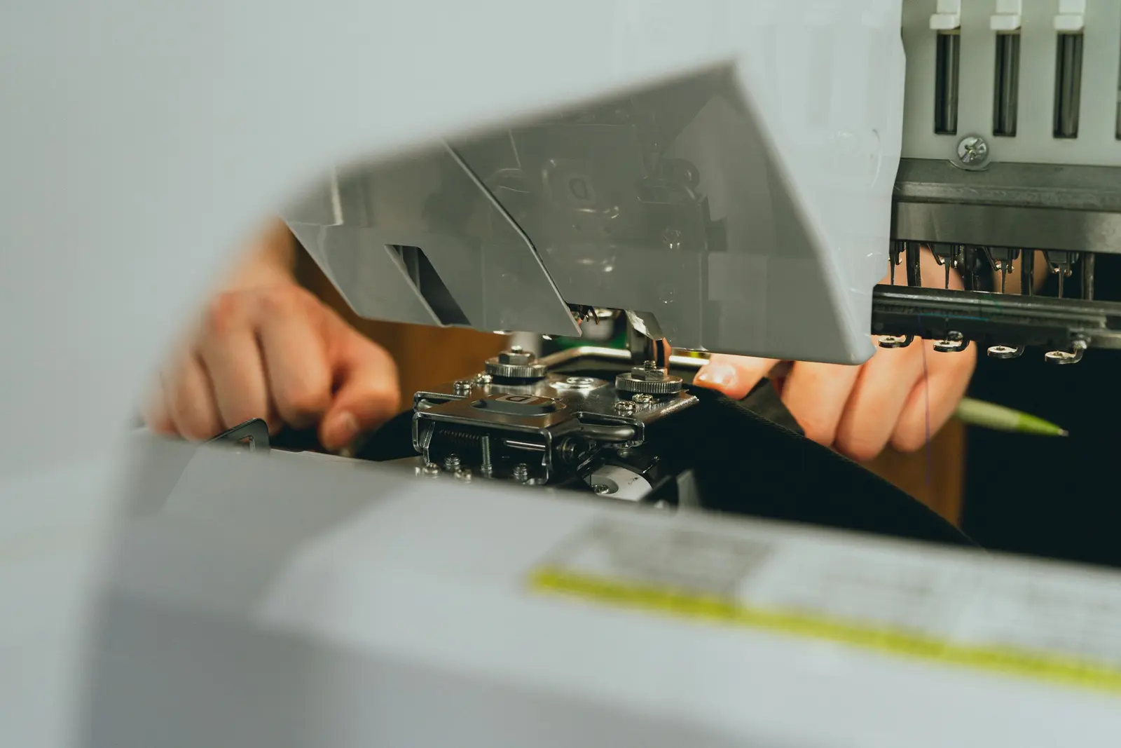 Manos trabajando una prenda en una máquina de costura industrial